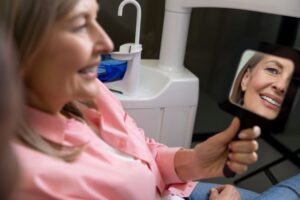 Happy middle-aged dental patient looking in mirror